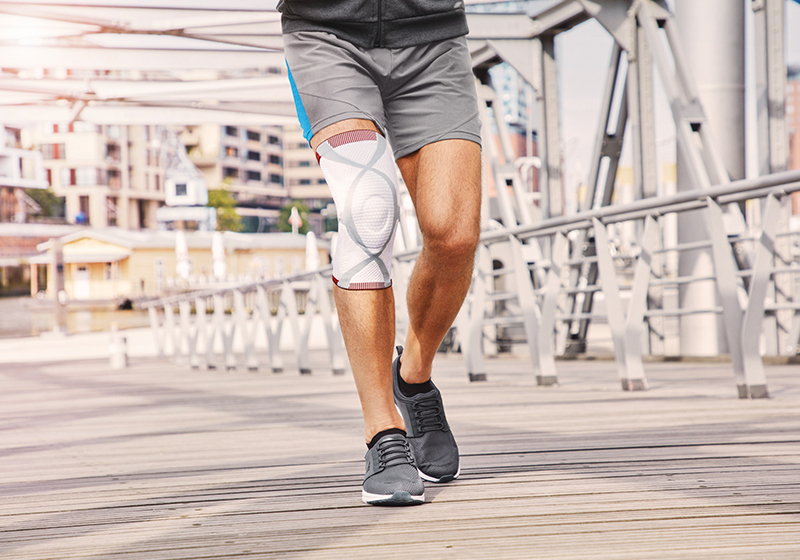 Man in shorts and a knee support runs up and across a wooden bridge Man in shorts and a knee support runs up and across a wooden bridge
